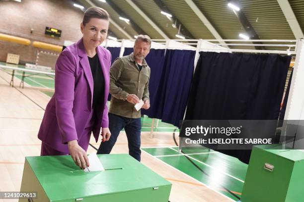 Danish Prime Minister Mette Frederiksen, also leader of Denmark's Social Democrats, casts her ballot as her husband Bo Tengberg looks on at a polling...