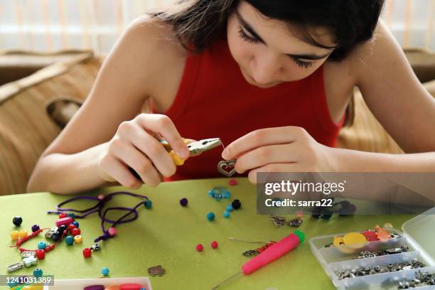 joven haciendo pulseras de cuentas - chicas pulseras fotografías e imágenes de stock