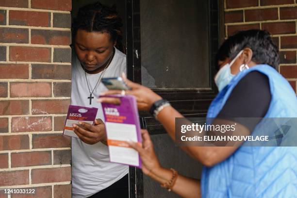 New Georgia Project canvasser Mardie Hill speaks to a resident about the upcoming primary election on May 23 in East Point, Georgia. - Under slate...