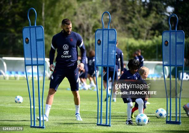 France's forward Karim Benzema plays with a child before a training session in Clairefontaine-en-Yvelines on June 1, 2022 as part of the team's...