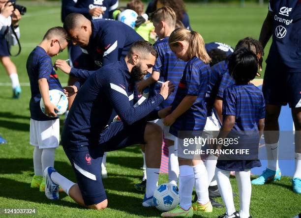 France's forward Kylian Mbappe and forward Karim Benzema sign autographs before a training session in Clairefontaine-en-Yvelines on June 1, 2022 as...