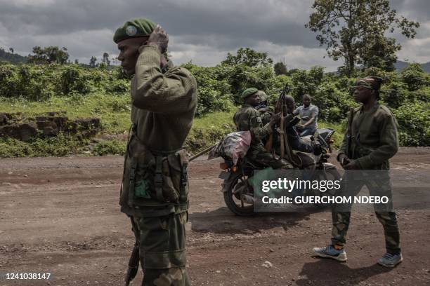 Motorcyclist carries soldiers as others patrol the area in Kibumba that was attacked by M23 rebels in clashes with the Congolese army, near the town...