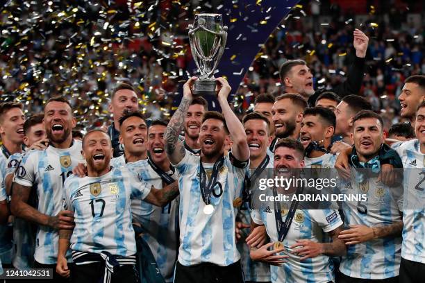 Argentina's striker Lionel Messi lifts the trophy as Argentina's players celebrate on the pitch after their victory in the 'Finalissima'...