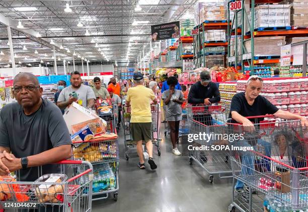 Shoppers wait in a check-out line at a Costco wholesale store in Orlando. Costco reported a double-digit rise in sales during the third quarter and...