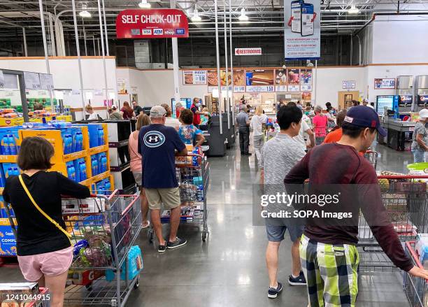 Shoppers wait in a check-out line at a Costco wholesale store in Orlando. Costco reported a double-digit rise in sales during the third quarter and...