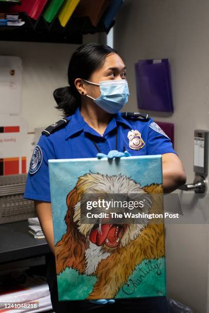 Officer Kat Claro displays a painting inside the TSA Lost and Found department at Dulles International Airport in Sterling, Virginia, on Wednesday,...