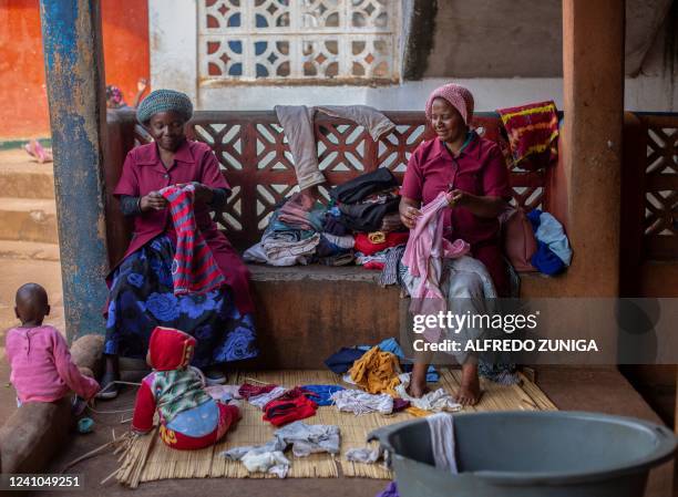 Two women fold and mend clothes while caring for babies in the courtyard of the Lemusica centre whose acronym in Portuguese means LEVANTE-SE MULHER Y...