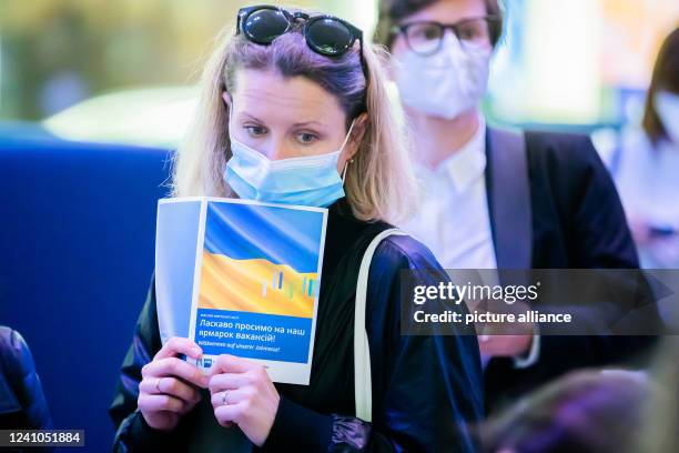 Woman holds the fair map with the Ukrainian flag at a job fair for Ukrainian refugees organized by the Berlin Chamber of Industry and Commerce and...