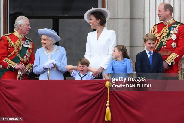 Britain's Prince Louis of Cambridge holds his ears as he stands next to Britain's Queen Elizabeth II and Britain's Prince Charles, Prince of Wales ,...