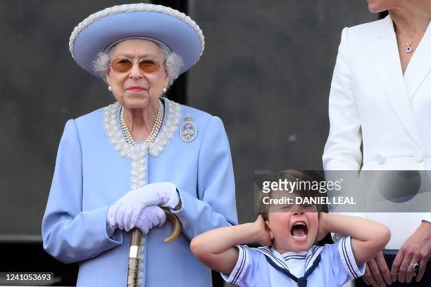 Britain's Prince Louis of Cambridge holds his ears as he stands next to Britain's Queen Elizabeth II to watch a special flypast from Buckingham...