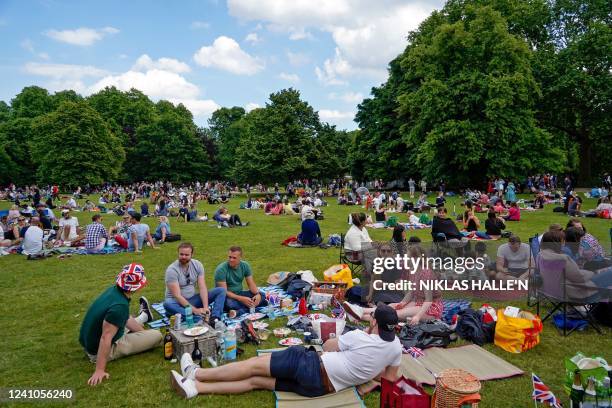 Members of the public, some with Union flag-themed memorabilia, relax in St James's Park near Buckingham Palace following the Platinum Jubilee...