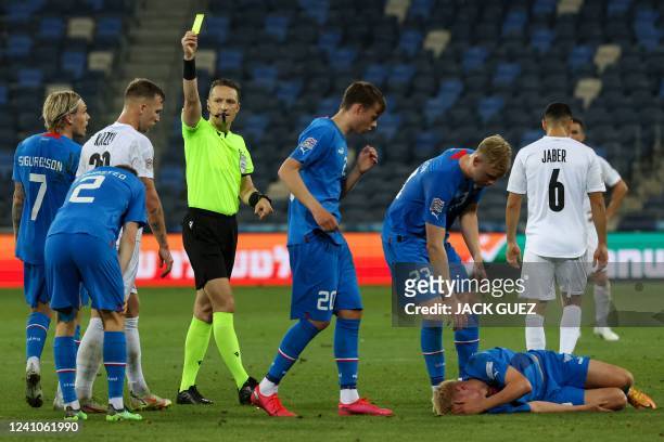 Latvian referee Andris Treimanis presents a yellow card to Israel's midfielder Eden Karzev for his foul on Iceland's midfielder Hakon Arnar...