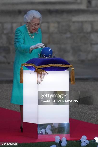 Britain's Queen Elizabeth II touches the Commonwealth Nations Globe to start the lighting of the Principal Beacon outside of Buckingham Palace in...