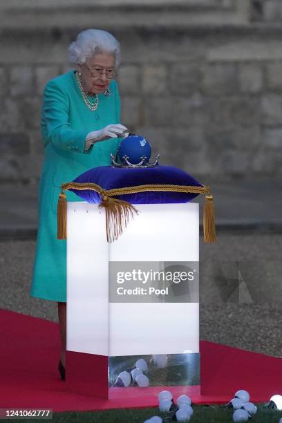 Britain's Queen Elizabeth II touches the Commonwealth Nations Globe to start the lighting of the Principal Beacon outside of Buckingham Palace in...