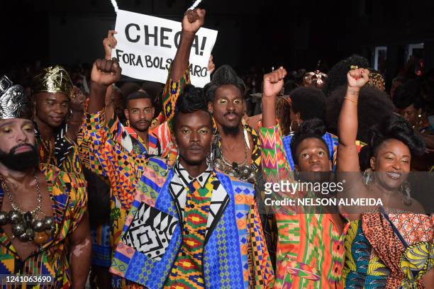 Model displays a placard reading "Enough! Bolsonaro Out" as he presents a creation by Meninos Rei during the Sao Paulo Fashion Week in Sao Paulo,...