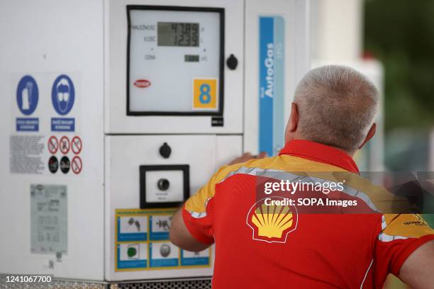 Shell gas station worker uses fuel distributor.