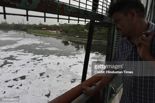 Man looking at the white froth flaoting in polluted Yamuna River at ITO Chhath Ghat on June 2, 2022 in New Delhi, India. While only 2% of Yamuna...