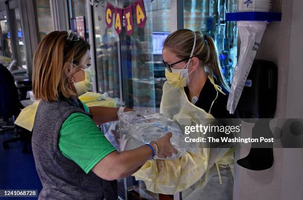 Shonda Grappe, a pediatric intensive care nurse, hands over supplies to Brittany Rowell, CCRN, in the pediatric ICU at Arkansas Children's Hospital...