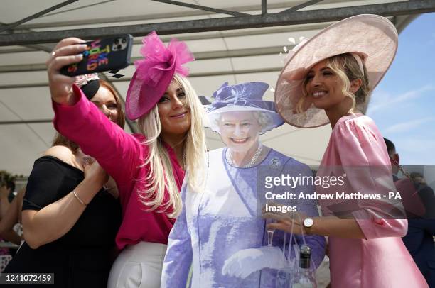 Racegoers take a selfie with a cardboard cut-out of the Queen ahead of Ladies Day during the Cazoo Derby Festival 2022 at Epsom Racecourse, Surrey....