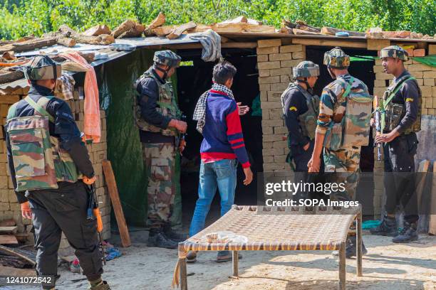 Indian paramilitary troopers inspect the attack site where assailants shot dead a migrant Hindu labour who was working at a brick factory in...