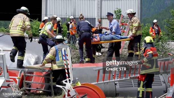 This video grab shows policemen and firemen rescuing a person from a derailed train on June 3, 2022 in Burgrain near Garmisch-Partenkirchen, southern...