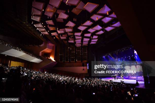 Fans listen as Venezuelan group San Luis performs during a concert at the Teresa Carreno Theatre in Caracas on May 1, 2022. - The dramatic drop in...