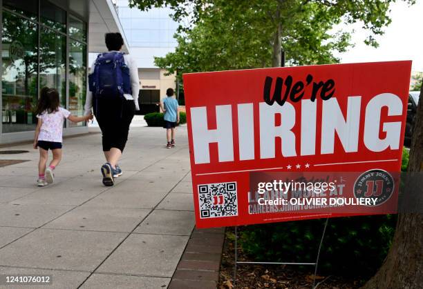 People walk past a "now hiring" sign posted outside of a restaurant in Arlington, Virginia on June 3, 2022. US employers added 390,000 jobs last...