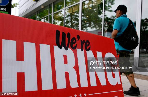 Man walks past a "now hiring" sign posted outside of a restaurant in Arlington, Virginia on June 3, 2022. US employers added 390,000 jobs last month,...