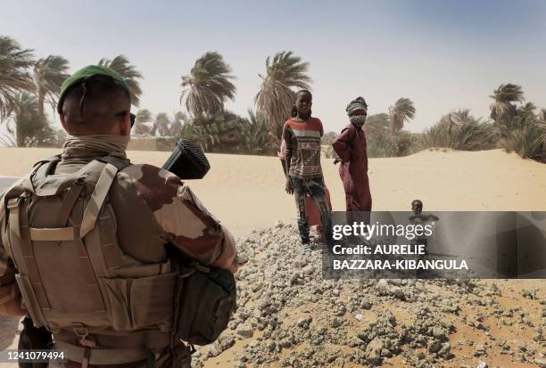 Children from Faya-Largeau poses in front of a Barkhane force soldier posted in front of a health center, in northern Chad, on June 2, 2022. The...