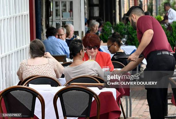 Waiter works at a restaurant in Alexandria, Virginia on June 3, 2022. - US employers added 390,000 jobs last month, the US Labor Department reported...