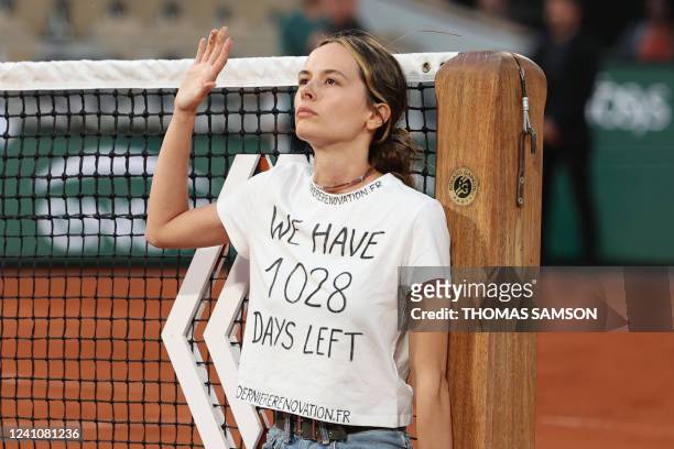 An activist gestures after attaching herself to the tennis net during the men's semi-final singles match between Norway's Casper Ruud and Croatia's...