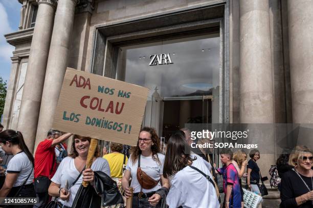 Demonstrator is seen in front of the Zara door holding a placard accusing Mayor Ada Colau of having ratified the new business hours for Sundays...
