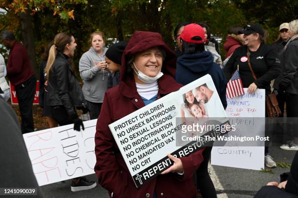 Jean Atkinson holds a sign outside before the Loudoun County school board meeting October 26, 2021 in Ashburn, VA. Loudoun County schools have been...