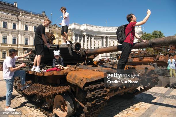 Teenagers play and pose for photography on a burned Russian tank, displayed for Ukrainians to see at Mykhailivska Square in downtown Kyiv, Ukraine,...