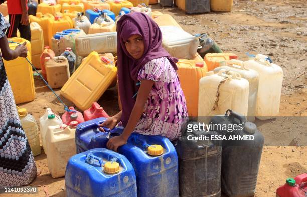 Yemeni girl waits as others fill their jerrycans with water at a makeshift camp for the internally displaced, in the northern Hajjah province on June...