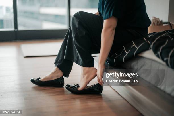 一個亞洲中�國中年成人正準備穿她的鞋子,然後離開她的公寓去上班 - women trying on shoes 個照片及圖片檔