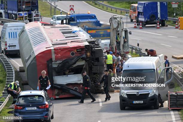 An overturned railway carriage lies on the side of a highway after it was lifted by cranes during salvage work at the site of a train derailment near...