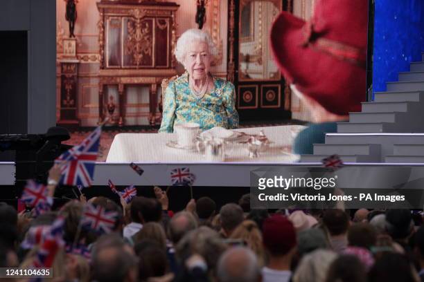 The crowd watching a film of Queen Elizabeth II having tea with Paddington Bear on a big screen during the Platinum Party at the Palace staged in...
