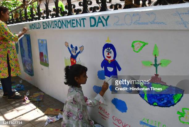 Children paint a wall highlighting planet earth on the eve of World Environment Day on June 4, 2022 in Mumbai, India.