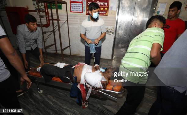 Rescue workers and civilians carry an injured victim to a hospital in Chittagong, after a fire broke out at a container storage facility in...