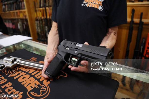 Salesman Chris Ruegg displays a Sig Sauer P320 9mm handgun from the display case at That Hunting Store on June 3, 2022 in Ottawa, Canada. - Canadians...