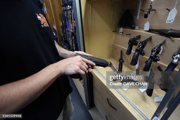 Salesman Chris Ruegg takes a Sig Sauer P320 9mm handgun from the display case at That Hunting Store on June 3, 2022 in Ottawa, Canada. - Canadians...