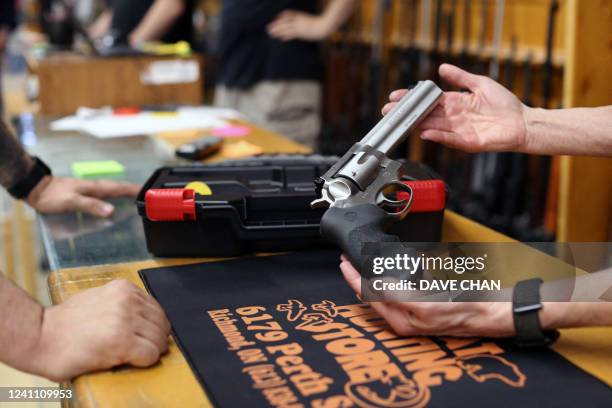 Jen Lavigne , co-owner of That Hunting Store, shows a customer a Ruger GP100 Magnum 357 on June 3, 2022 in Ottawa, Canada. - Canadians rushed to buy...