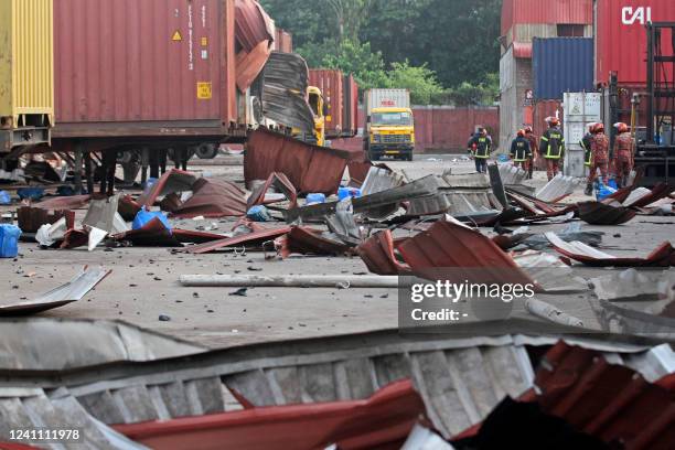 Firefighters walk amid the debris at the site where a fire broke out at a container storage facility in Sitakunda, about 40 km from the key port of...