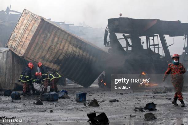 Firefighters carry the dead body of a victim from the site after a fire broke out at a container storage facility in Sitakunda, about 40 km from the...