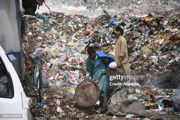 Pakistani garbage collectors collect usable items from a dump site on the eve of World Environment Day in Karachi on June 04, 2022. World Environment...