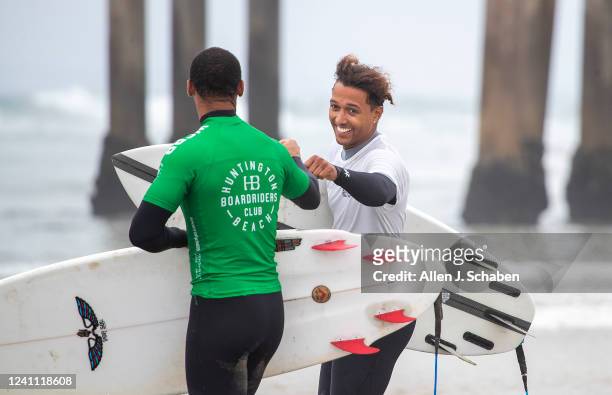 Huntington Beach, CA Kayiita Johnson, right, bumps fists with a fellow surfer as hey head out to compete in a surf competition during A Great Day in...