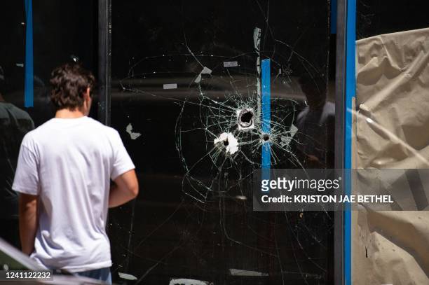 Pedestrian walks past bullet holes in the window of a store front on South Street in Philadelphia, Pennsylvania, on June 5, 2022. / The erroneous...