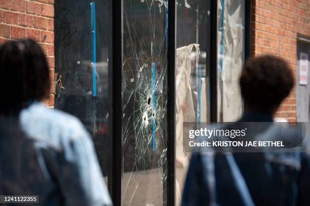 Pedestrians walk past bullet holes in the window of a store front on South Street in Philadelphia, Pennsylvania, on June 5, 2022. / The erroneous...