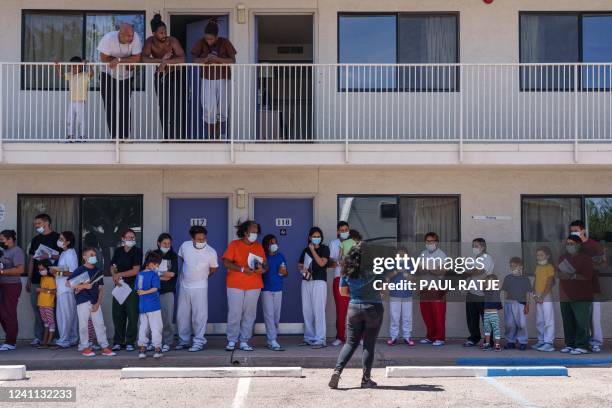 Families from Latin America are greeted by shelter staff after arriving at a motel being used as a shelter run by the non-profit Colores United,...